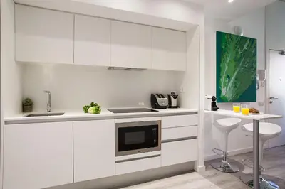 a white kitchen with white cabinets and a microwave at Habitat Apartments ADN in Barcelona