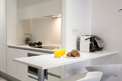 a white kitchen with a table with a glass of orange juice at Habitat Apartments ADN in Barcelona