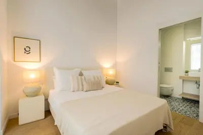 a white bedroom with a white bed and a window at CATERINA Editorial in Barcelona