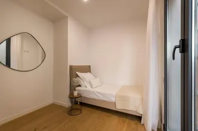 a white bedroom with a bed and a mirror at CATERINA Editorial in Barcelona