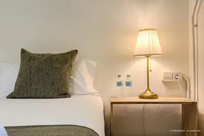 a bed with a lamp and two water bottles on a table at Sagrada Familia 360 in Barcelona