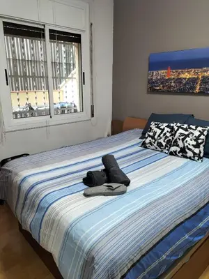 a bed with a pair of shoes sitting on it at Room in shared appartment close to Camp Nou in Hospitalet de Llobregat