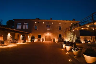 a large building with a courtyard at night at Hotel-Masia Can Farrés in El Bruc