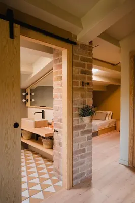 a room with a brick wall and a bedroom at Hotel-Masia Can Farrés in El Bruc