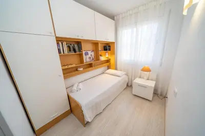 a small bedroom with a white bed and a window at HomeHolidaysRentals Bluemar-Costa Barcelona in Pineda de Mar
