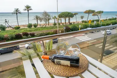 a table with a bottle of wine and glasses on a balcony at HomeHolidaysRentals Noelani- Costa Barcelona in Pineda de Mar