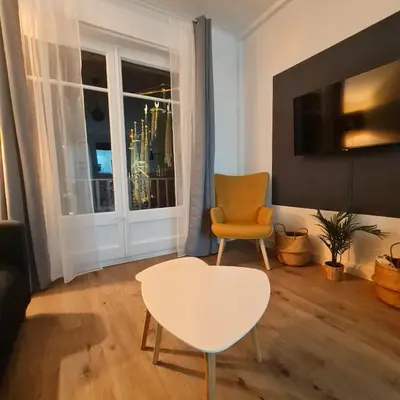 a living room with a table and a chair and a window at G74 AVENIDA GAUDI nice 4 bedrooms apartment with balcony with views of the Basilica Sagrada Familia in Barcelona