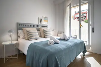 a white bedroom with a bed with towels on it at Habitat Apartments Arenas Parc in Barcelona
