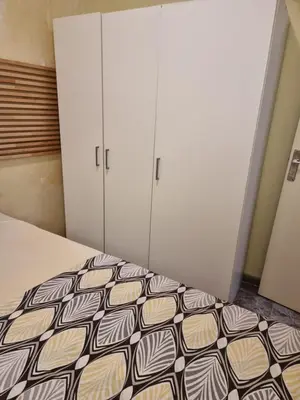 a bedroom with a bed and two white cabinets at 2 bedrm BCN down AC WIFI 30 nigths min in Barcelona
