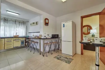 a kitchen with a refrigerator and a table and chairs at Villa ilusions en Olivella, Sitges, Barcelona in Olivella