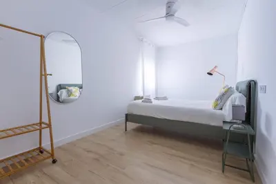 a white bedroom with a bed and a mirror at Feel Welcome Barcelona # SPLAU in Cornellà de Llobregat