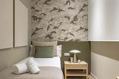 a bedroom with a bed with a floral wallpaper at Ola Living Hostal Diagonal in Barcelona