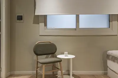 a chair and a table in a room with a window at Ola Living Hostal Diagonal in Barcelona