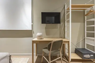 a room with a desk and a tv and a bed at Ola Living Hostal Diagonal in Barcelona