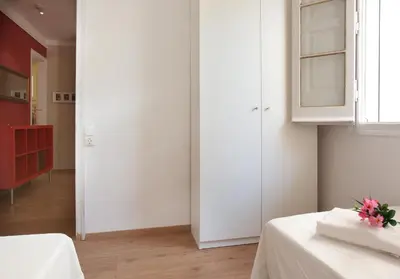 a white room with two beds and a window at Centric Apartment El Molino Theater p1 in Barcelona