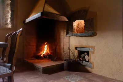 a dining room with a table and a fireplace at Masia Casa Nova de n'Illa in Montseny