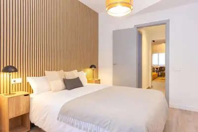 a bedroom with a white bed and a wooden wall at Duplex with terrace near Bcn in Terrassa