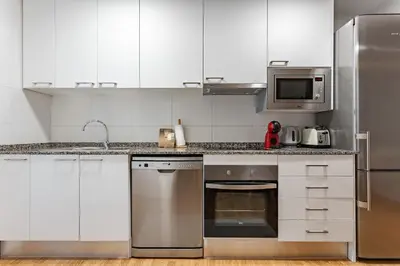 a kitchen with white cabinets and stainless steel appliances at Ola Living Sagrada Familia in Barcelona