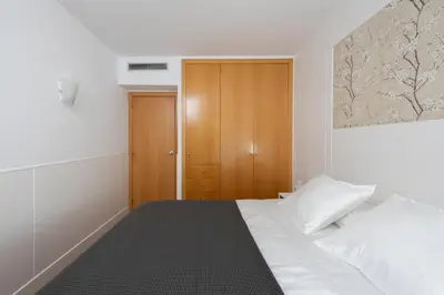 a bedroom with a white bed and a wooden cabinet at Marion House Barcelona in Barcelona