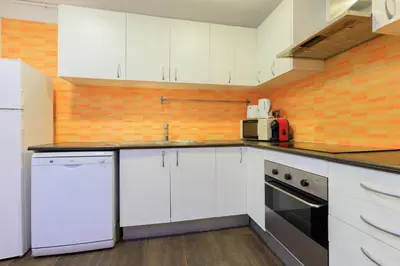 a kitchen with white appliances and an orange wall at Housalia Corsega - Apartment 3 bedrooms next to Sagrada Familia in Barcelona