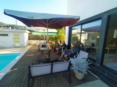 a group of people sitting on a patio with an umbrella at Villa Franz House Casa Principal in Canyelles