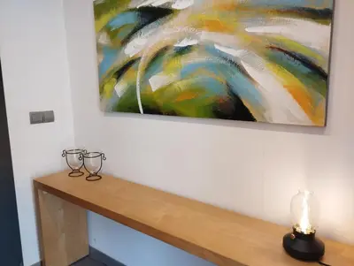 a painting hanging on a wall with two glasses on a table at Villa Franz House Casa de Invitados in Canyelles