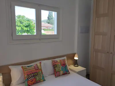 a bedroom with a bed with two pillows and a window at Villa Franz House Casa de Invitados in Canyelles
