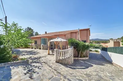 a house with a fence and an umbrella at Villa lluna en Olivella, Sitges, Barcelona in Olivella