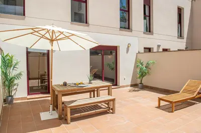 a patio with a table and an umbrella and a bench at The Orbit Apartments in Barcelona