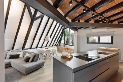 a kitchen and living room with a couch and a table at Enjoy Apartments La Riera Penthouse in Barcelona