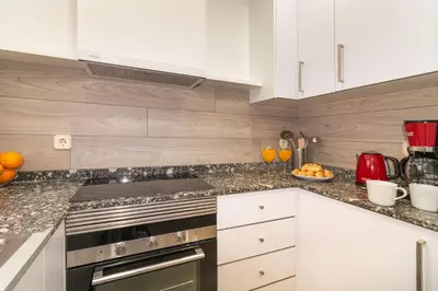 a kitchen with white cabinets and granite counter tops at Central & Fully Equipped Apartment in Eixample Next to Metro, Sleeps 5 in Barcelona
