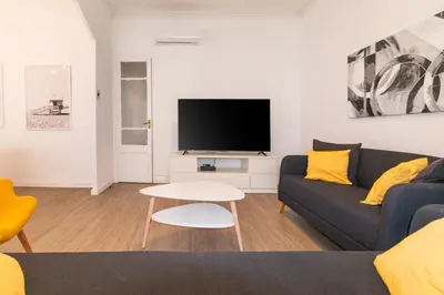 a living room with a couch and a tv at Central & Fully Equipped Apartment in Eixample Next to Metro, Sleeps 5 in Barcelona
