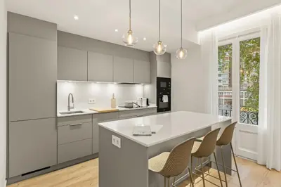 a kitchen with white cabinets and a kitchen island with stools at Modern & stylish apartment in Barcelona in Barcelona