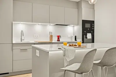 a kitchen with white cabinets and a island with chairs at Modern & stylish apartment in Barcelona in Barcelona