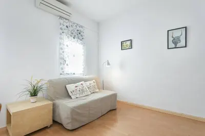 a white living room with a couch and a table at ApartEasy - Lightly, central and quiet apartment in Barcelona