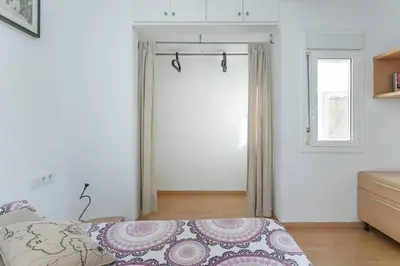 a white bedroom with a bed and a window at ApartEasy - Lightly, central and quiet apartment in Barcelona