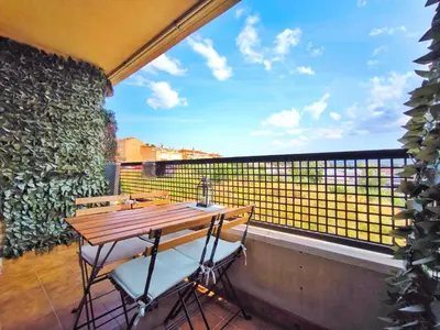a balcony with a wooden table and two chairs at Duplex con piscina en Rubí in Rubí