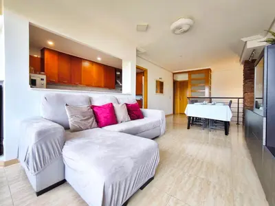 a living room with a white couch with pink pillows at Duplex con piscina en Rubí in Rubí