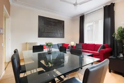 a dining room with a table and a red couch at Elegance and Comfort in Barcelona, 4Bedroom Apartment in the Most Exclusive Area in Barcelona