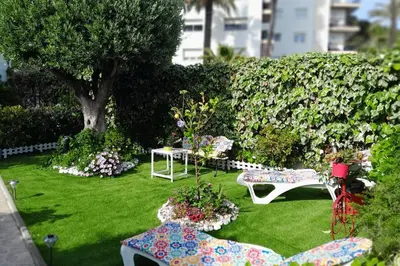 a garden with two chairs and a table and flowers at HomeHolidaysRentals Ancora - Costa Barcelona in San Pol de Mar