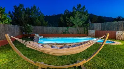 a hammock in a yard next to a pool at Villa Sitges El Olivo High Comodity AC Pool Heated 30º Optional Real Garden Pool XXL 10 min drive from Sitges in Olivella