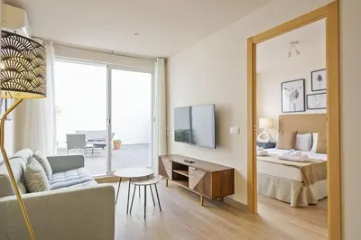 a bedroom with a bed and a living room with a mirror at Alcam Galileu in Barcelona