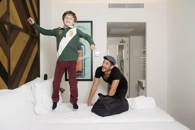 two young boys jumping on top of a bed at Praktik Vinoteca in Barcelona