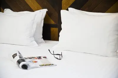 a pair of glasses and a magazine on a bed at Praktik Vinoteca in Barcelona