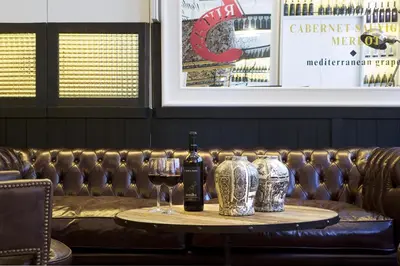 a table with two glasses of wine and a couch at Praktik Vinoteca in Barcelona