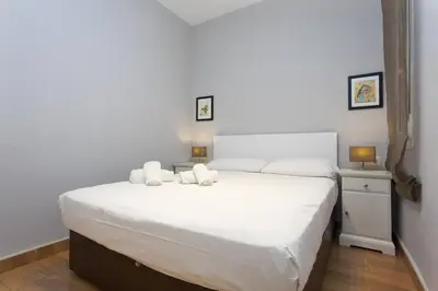 a bedroom with a large white bed with two candles on it at Bright & Spacious Family Flat in Central Barcelona in Barcelona