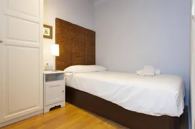 a bedroom with a white bed and a night stand at Bright & Spacious Family Flat in Central Barcelona in Barcelona