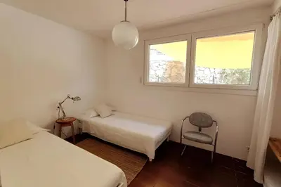 a room with two beds and a chair and a window at Casa Can Bellavista Barcelona town house in Premia de Dalt