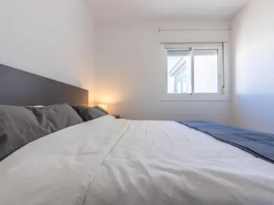 a white bedroom with a bed and a window at Apartment Zafiro by Interhome in Cubelles