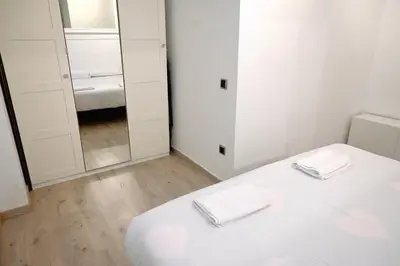 a white bedroom with a bed and a mirror at Homenfun Barcelona Guinardó Hospital Sant Pau in Barcelona